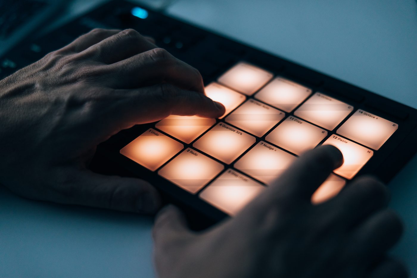 Hands on a glowing pad controller in blue light